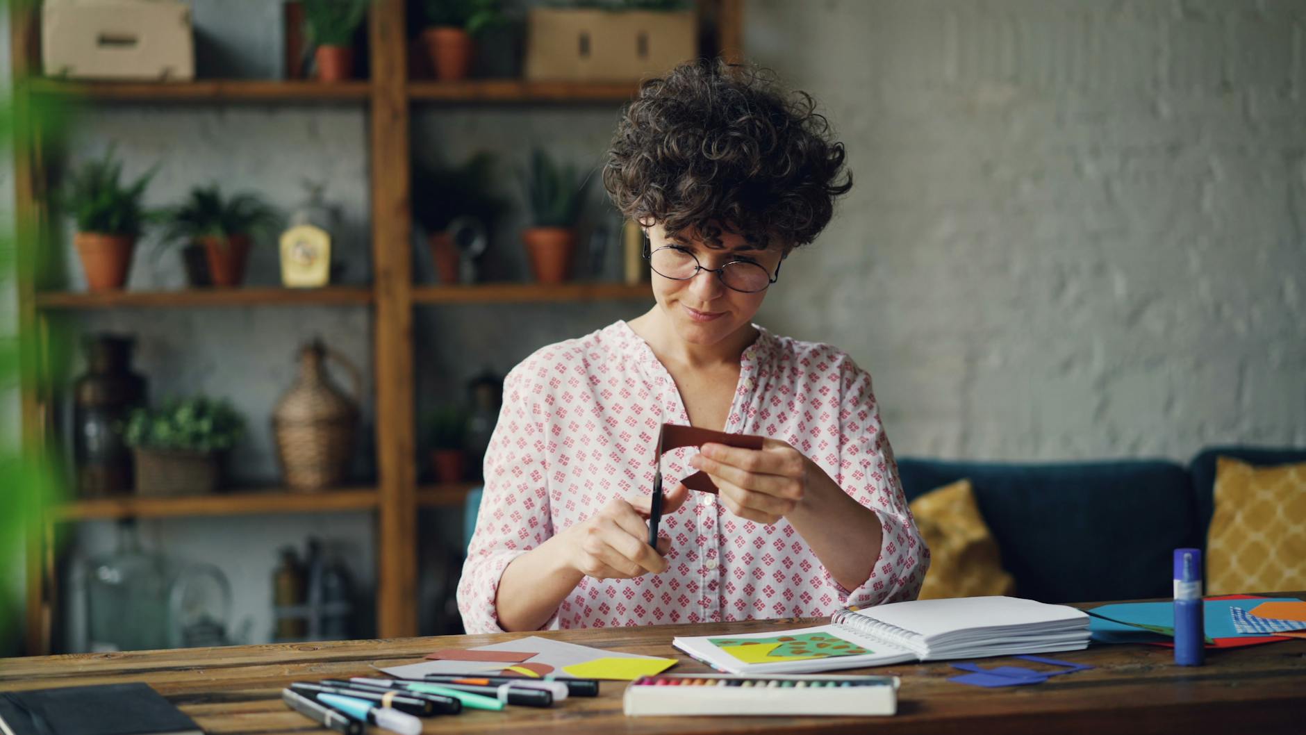 Kobieta wycina papierowe dekoracje w przytulnym domowym wnętrzu
