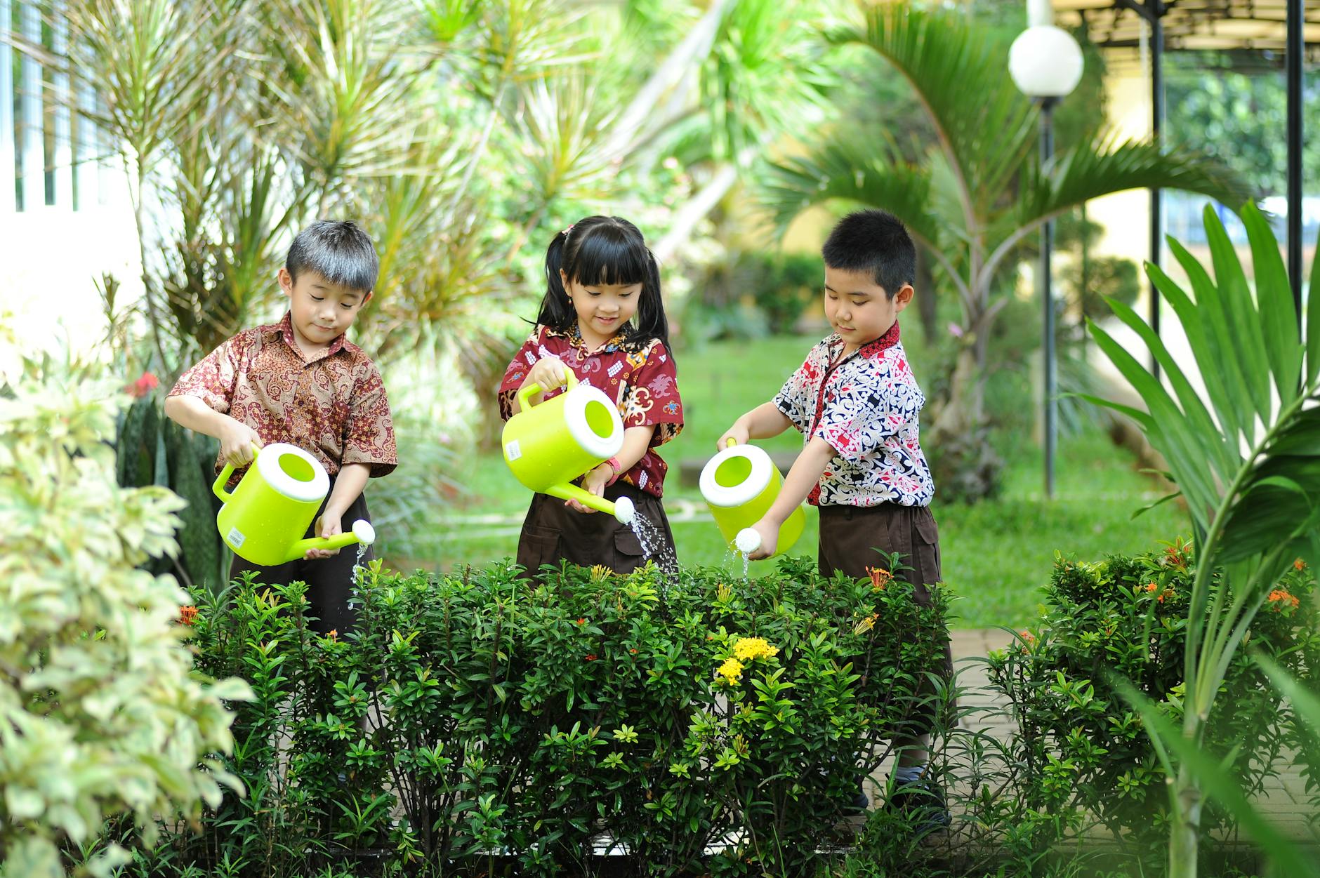 Niezwykłe włoskie ogrody botaniczne, gdzie dzieci uczą się ekologii i klimatu Dzieci podlewają rośliny zielonymi konewkami w włoskim ogrodzie botanicznym