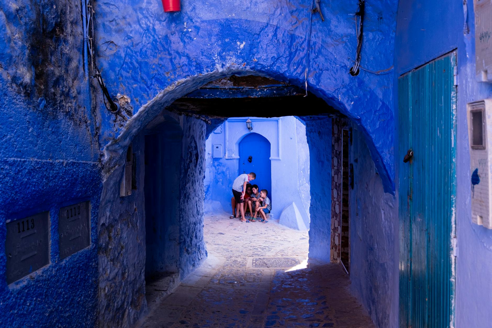 Dzieci bawią się w niebieskiej uliczce Chefchaouen w Maroku