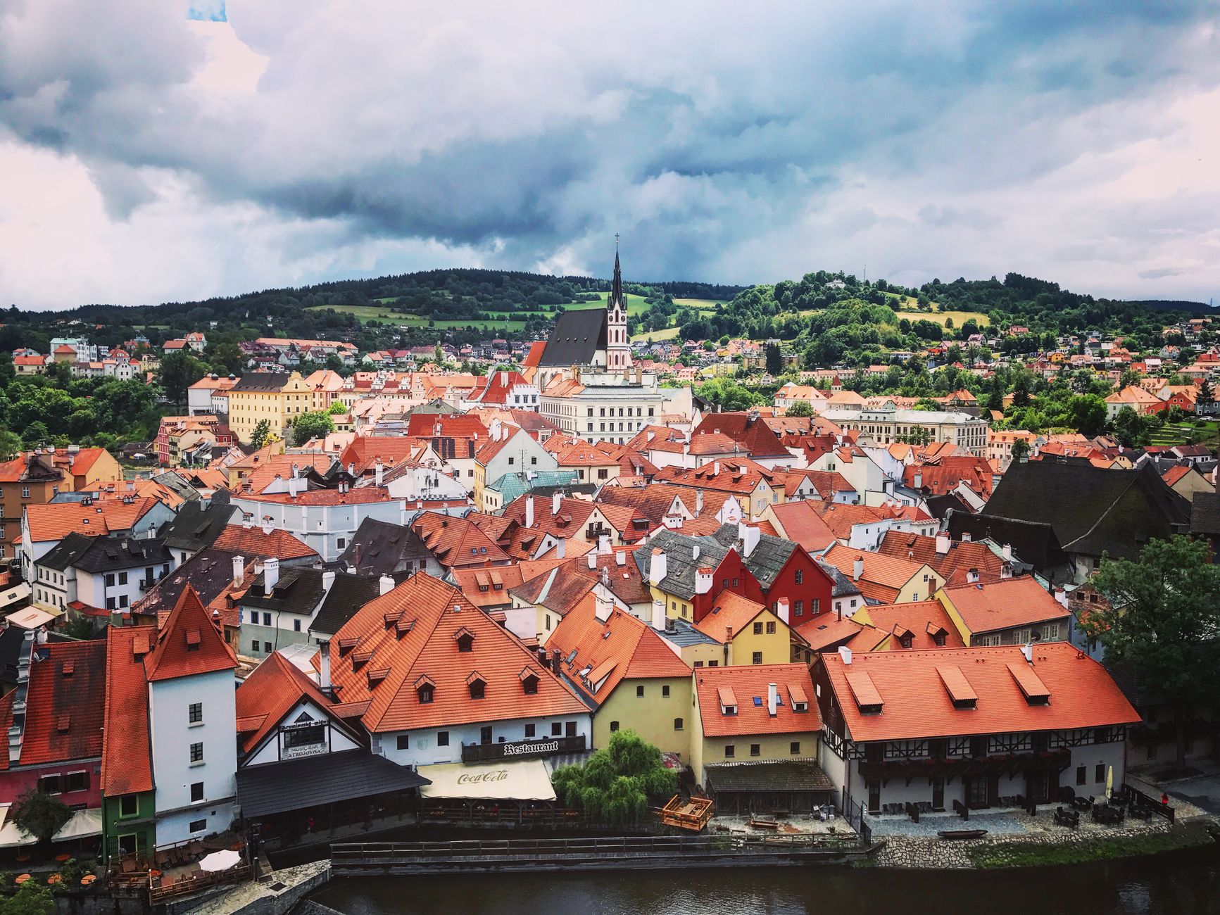 Panorama Českiego Krumlova z czerwonymi dachami i zielonym wzgórzem