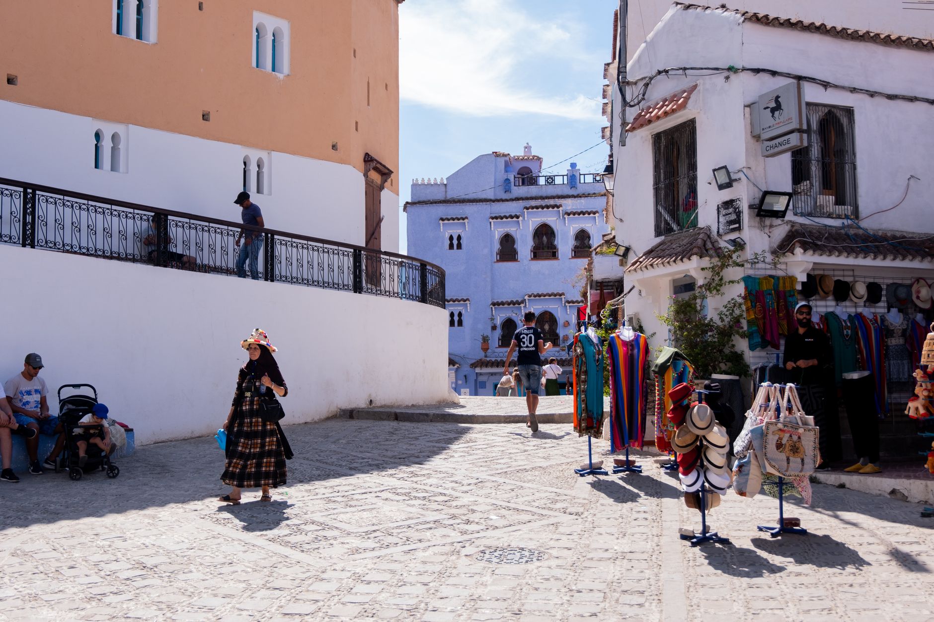 Słoneczna ulica Chefchaouen z lokalnymi sklepami i spacerującymi ludźmi